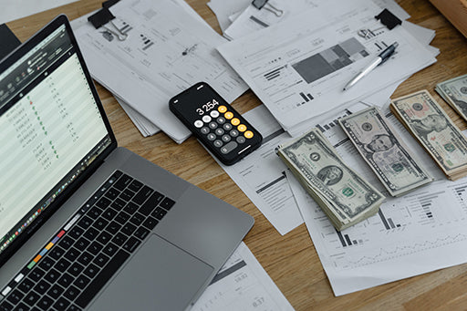 Desk with computer and calculator with money in piles being sorted.